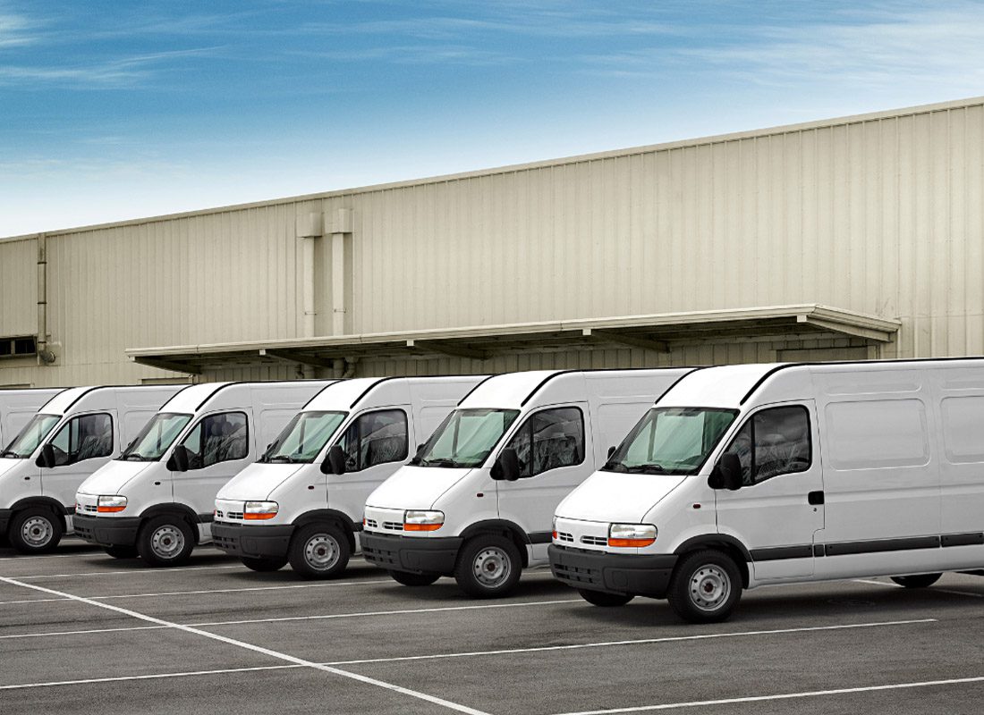 Business Auto Insurance - Fleet of Vans Sitting Against a Warehouse
